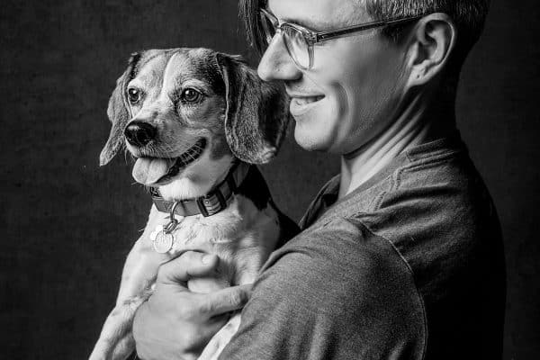 a black and white portrait of a man holding his small dog